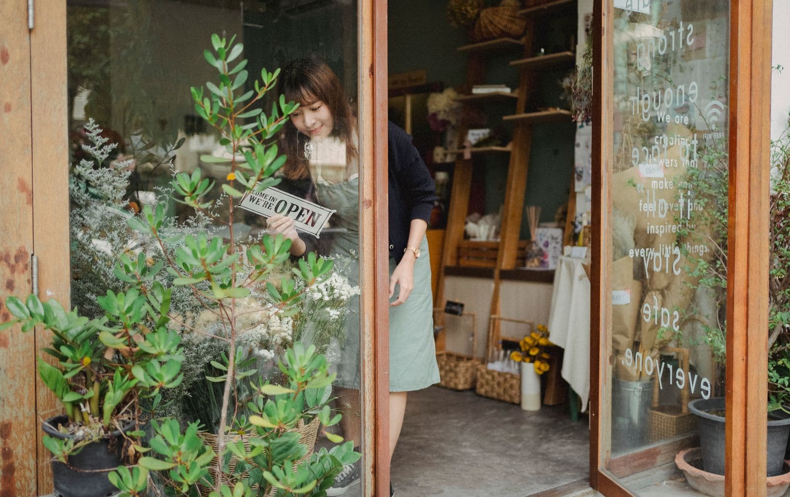 一位亞洲小型店主翻開營業招牌，準備開店